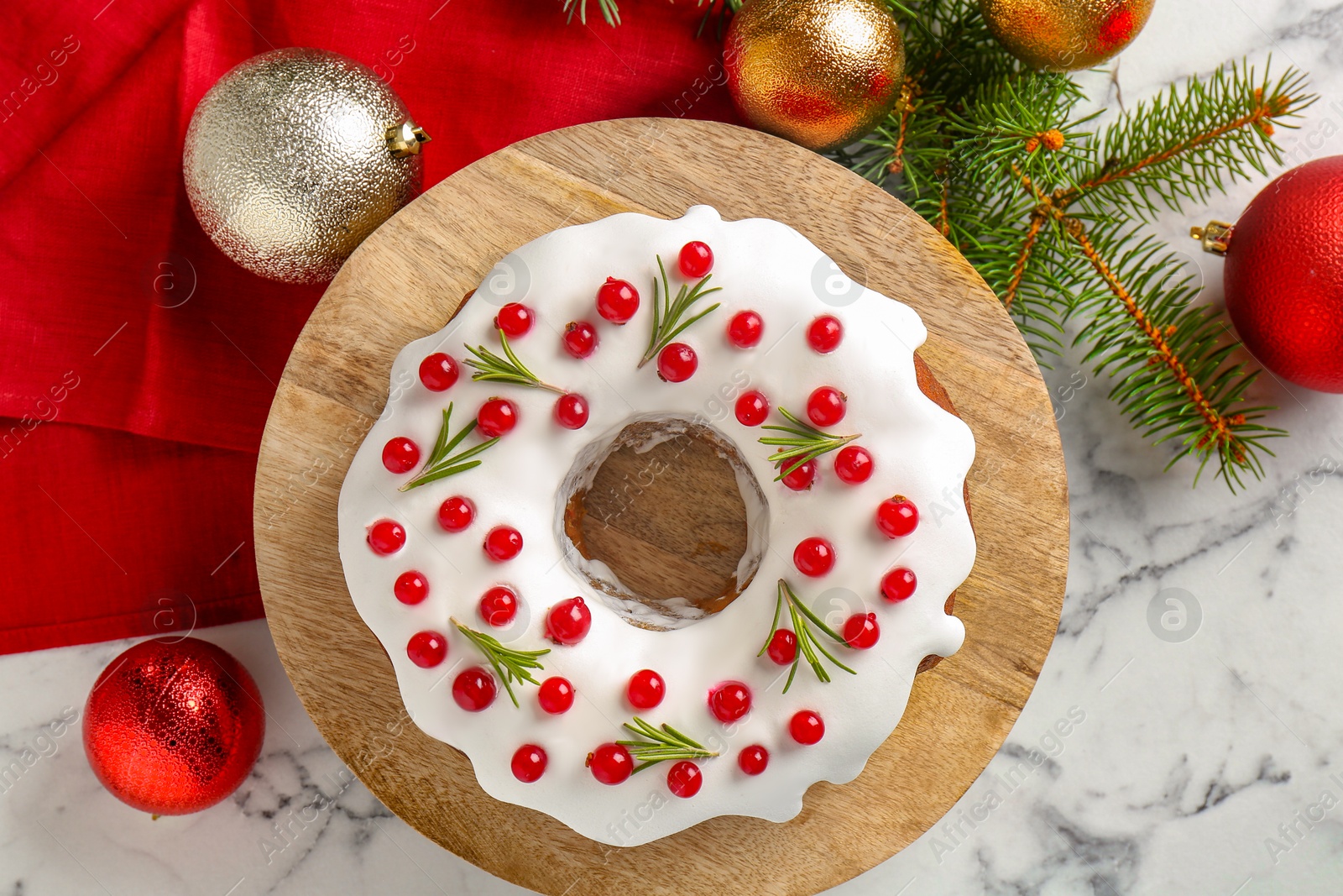 Photo of Beautifully decorated Christmas cake, fir branches and baubles on white marble table, flat lay