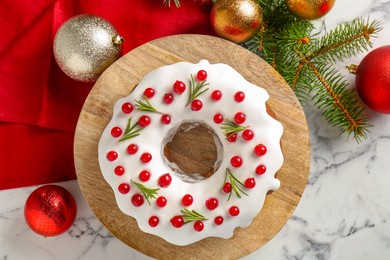 Photo of Beautifully decorated Christmas cake, fir branches and baubles on white marble table, flat lay