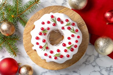 Photo of Beautifully decorated Christmas cake, fir branches and baubles on white marble table, flat lay