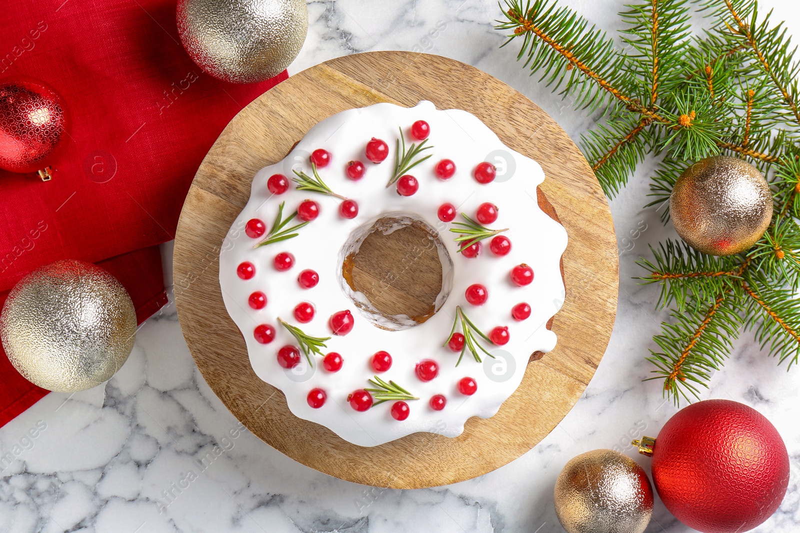 Photo of Beautifully decorated Christmas cake, fir branches and baubles on white marble table, flat lay