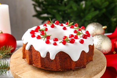 Photo of Traditional Christmas cake decorated with red currants and rosemary on table, closeup