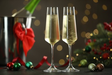 Photo of Delicious champagne in glasses and Christmas decor on grey table against blurred lights