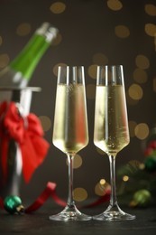 Photo of Delicious champagne in glasses and Christmas decor on grey table against blurred lights