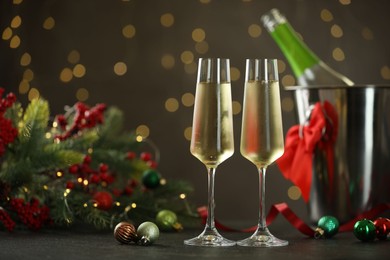 Photo of Delicious champagne in glasses and Christmas decor on grey table against blurred lights, space for text