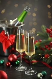 Photo of Delicious champagne in glasses and Christmas decor on grey table against blurred lights