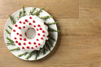 Photo of Traditional Christmas cake decorated with red currants and rosemary on wooden table, top view. Space for text