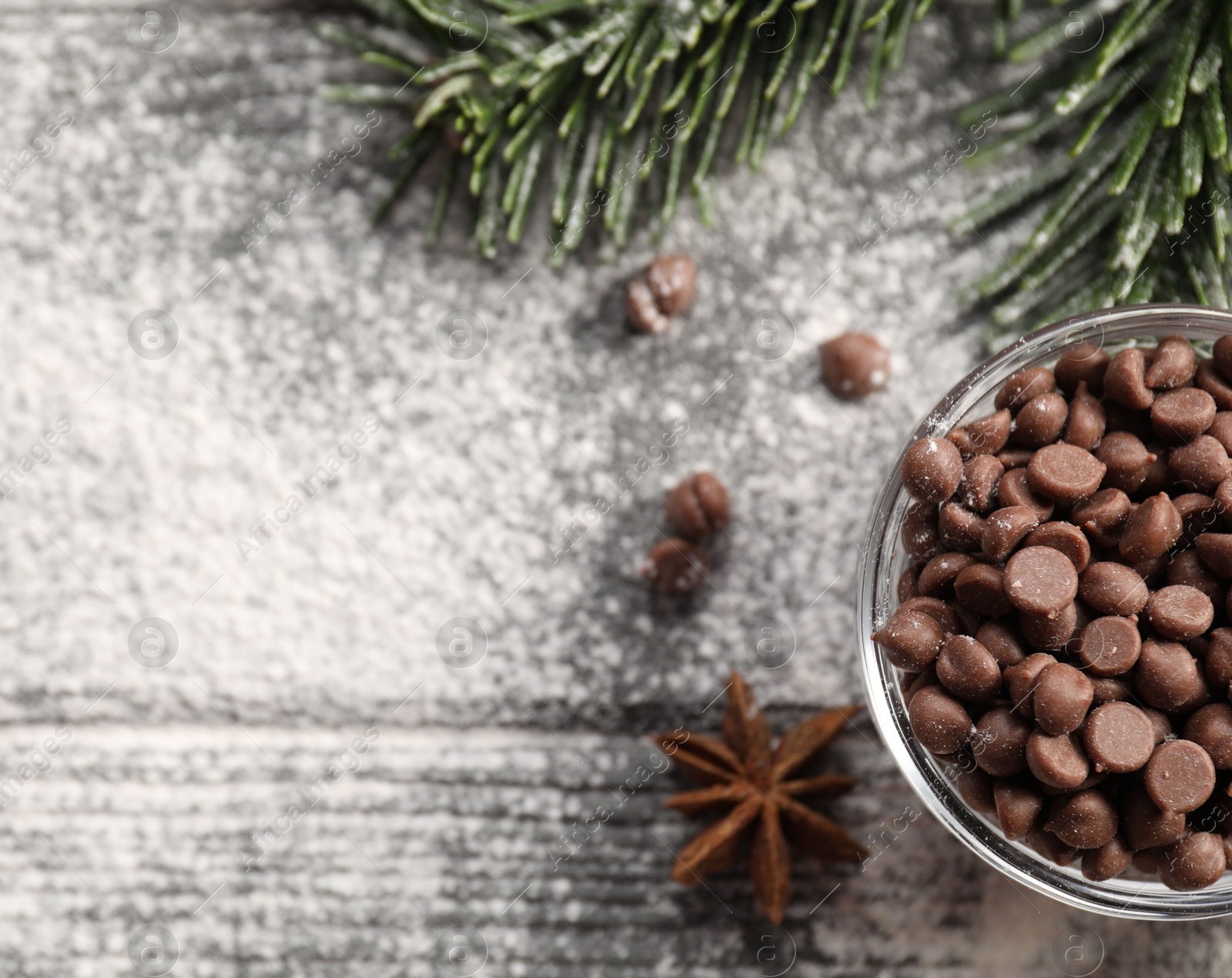 Photo of Chocolate chips, anise, flour and fir tree branches on wooden table, top view with space for text. Christmas season