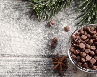 Photo of Chocolate chips, anise, flour and fir tree branches on wooden table, top view with space for text. Christmas season