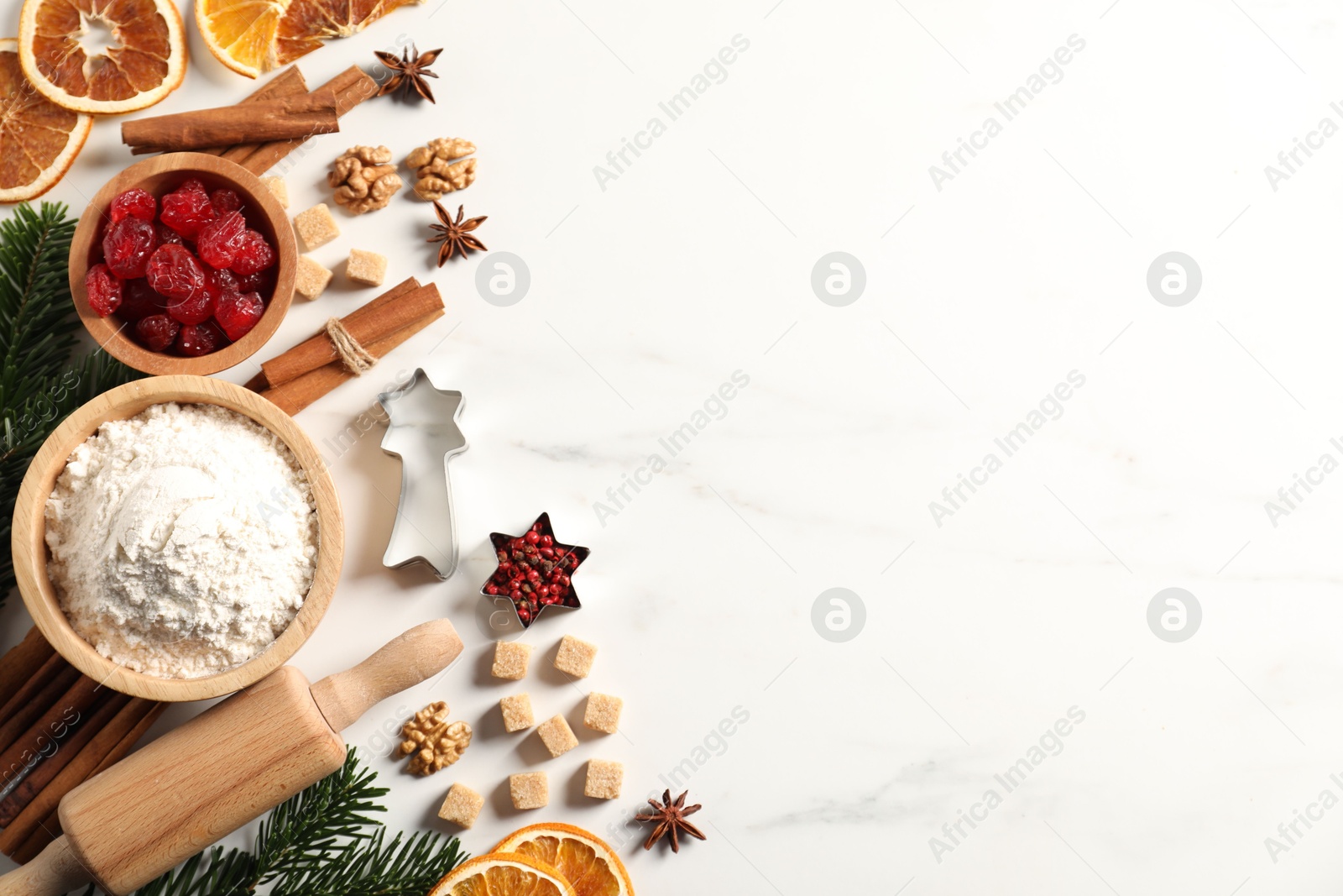 Photo of Different aromatic spices and fir tree branches on white table, flat lay with space for text. Christmas season