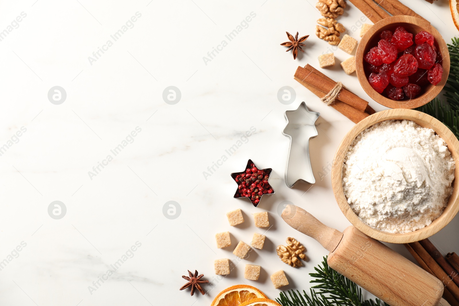 Photo of Different aromatic spices and fir tree branches on white table, flat lay with space for text. Christmas season