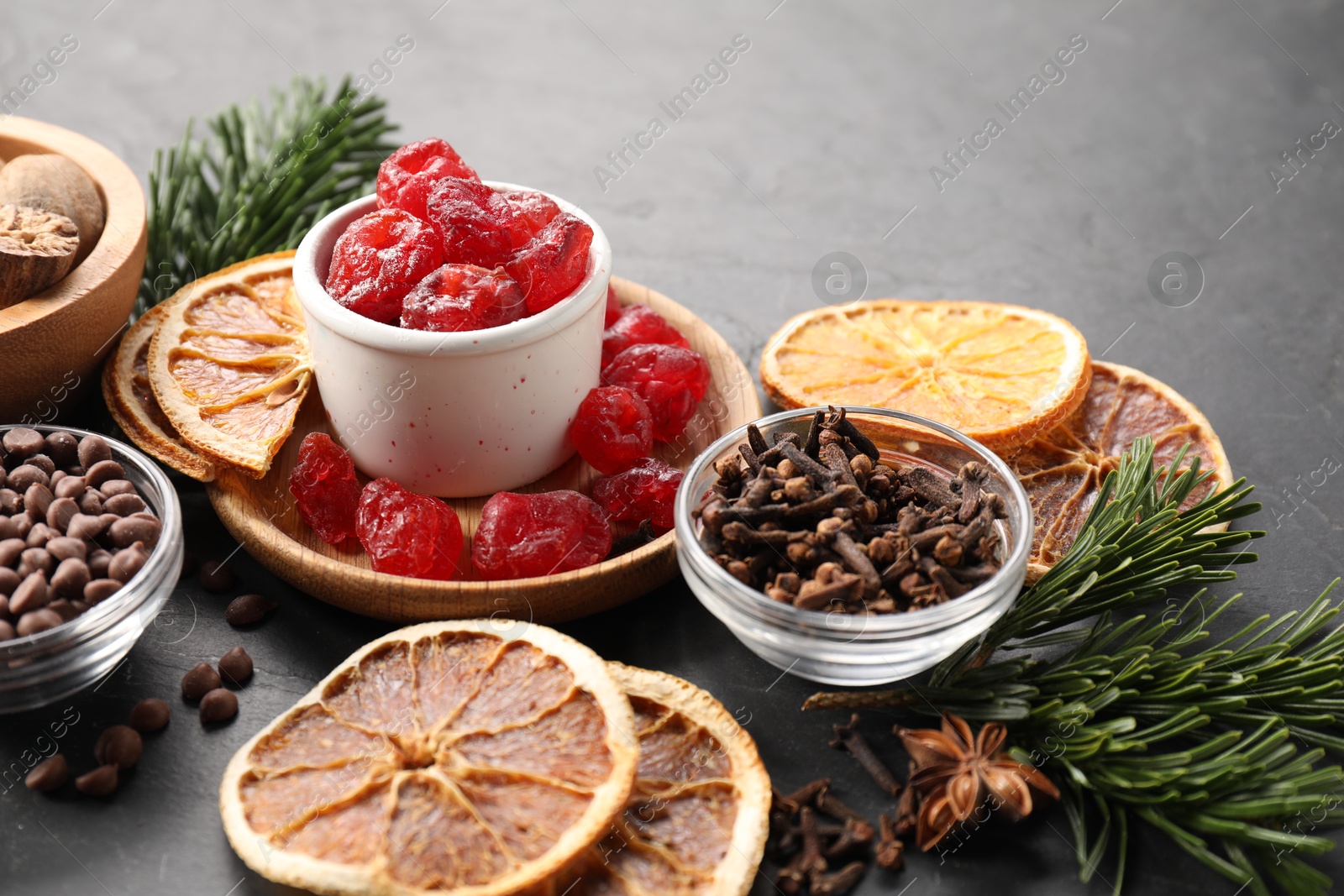 Photo of Different aromatic spices and fir tree branches on black table. Christmas season