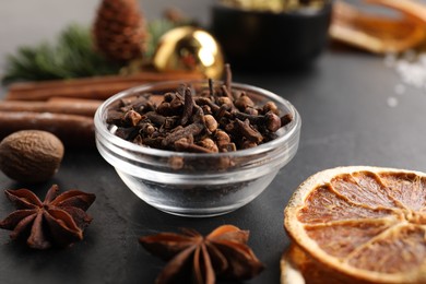 Photo of Different aromatic spices on black table, closeup. Christmas season