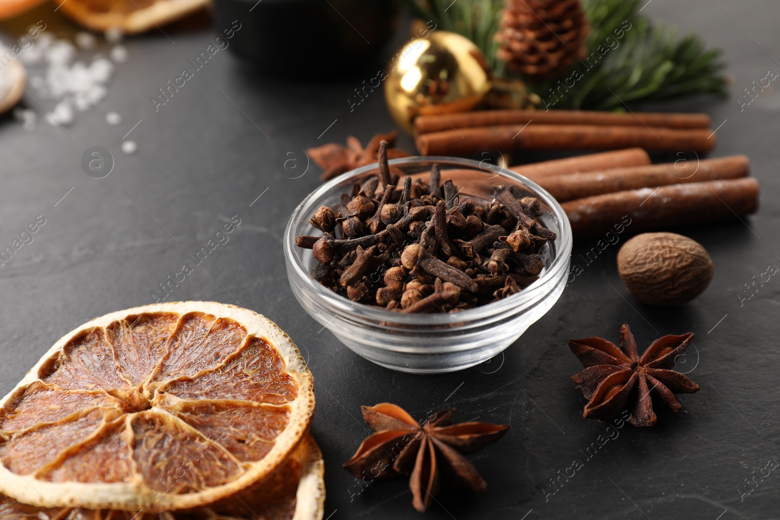 Photo of Different aromatic spices on black table, closeup. Christmas season