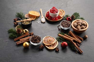 Photo of Different aromatic spices and fir tree branches on black table. Christmas season