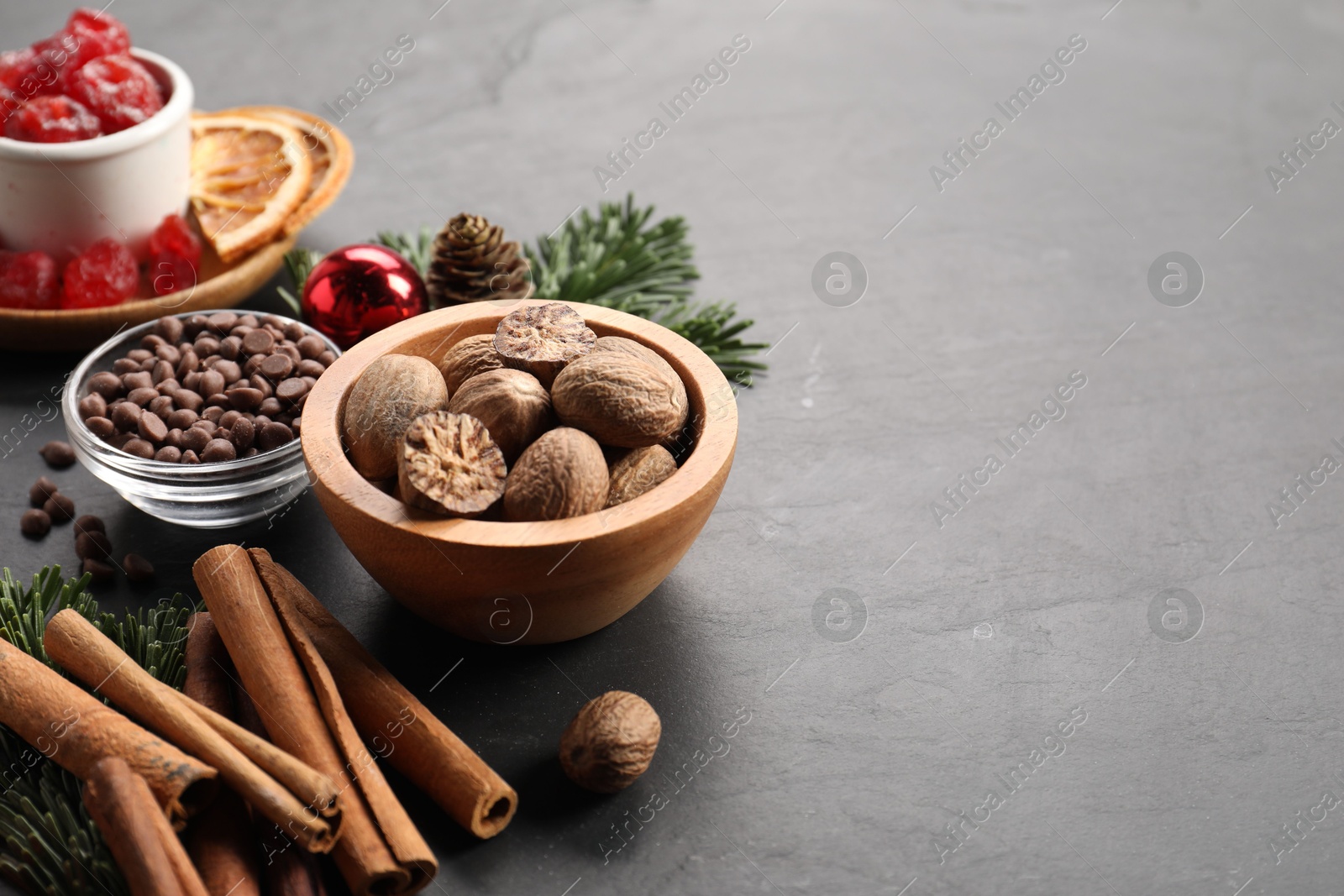 Photo of Different aromatic spices on black table, closeup with space for text. Christmas season