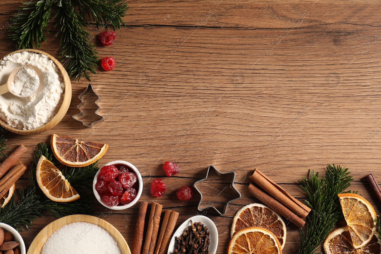 Photo of Different aromatic spices and fir tree branches on wooden table, flat lay with space for text. Christmas season