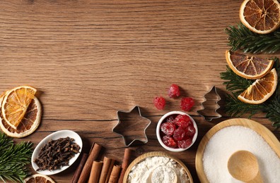 Photo of Different aromatic spices and fir tree branches on wooden table, flat lay with space for text. Christmas season