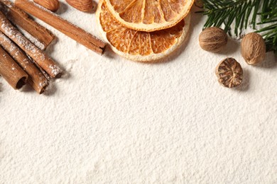 Photo of Different aromatic spices and fir tree branch on table, flat lay with space for text. Christmas season