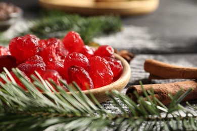 Photo of Candied cranberries, cinnamon sticks and fir tree branch on wooden table, closeup. Christmas season