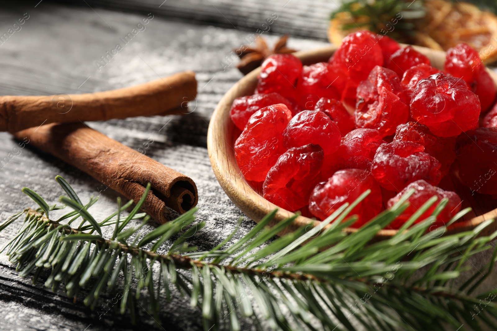 Photo of Candied cranberries, cinnamon sticks and fir tree branch on wooden table, closeup. Christmas season