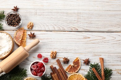 Photo of Different aromatic spices and fir tree branches on white wooden table, flat lay with space for text. Christmas season