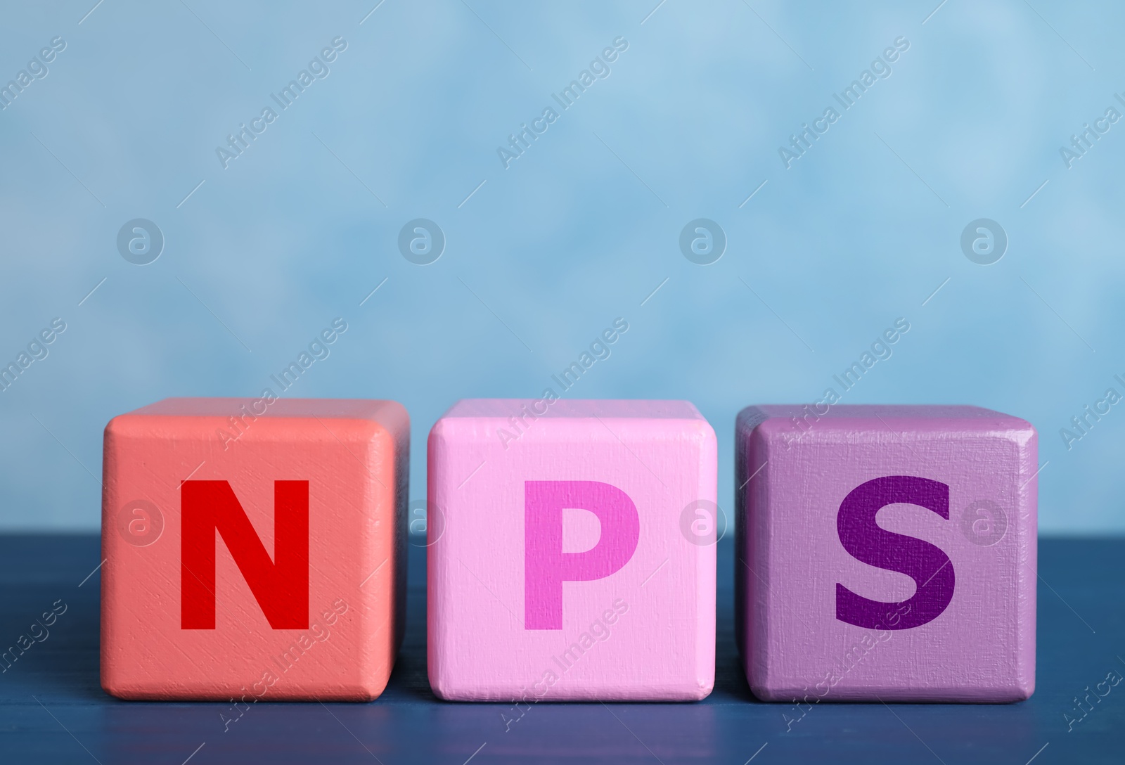 Image of NPS (net promoter score) abbreviation made of wooden cubes against light blue background