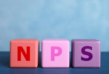 Image of NPS (net promoter score) abbreviation made of wooden cubes against light blue background