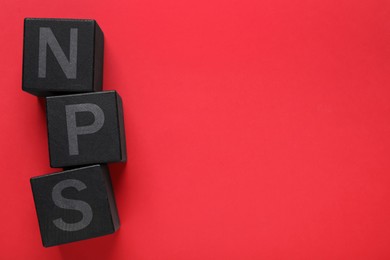 Image of NPS (net promoter score) abbreviation made of black cubes on red background, top view