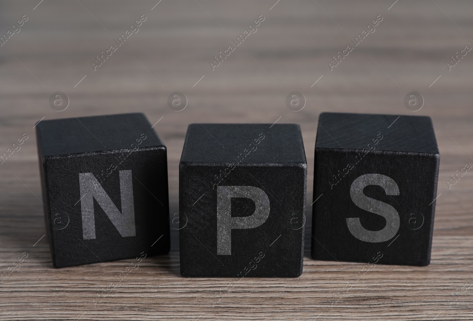 Image of NPS (net promoter score) abbreviation made of black cubes on wooden table