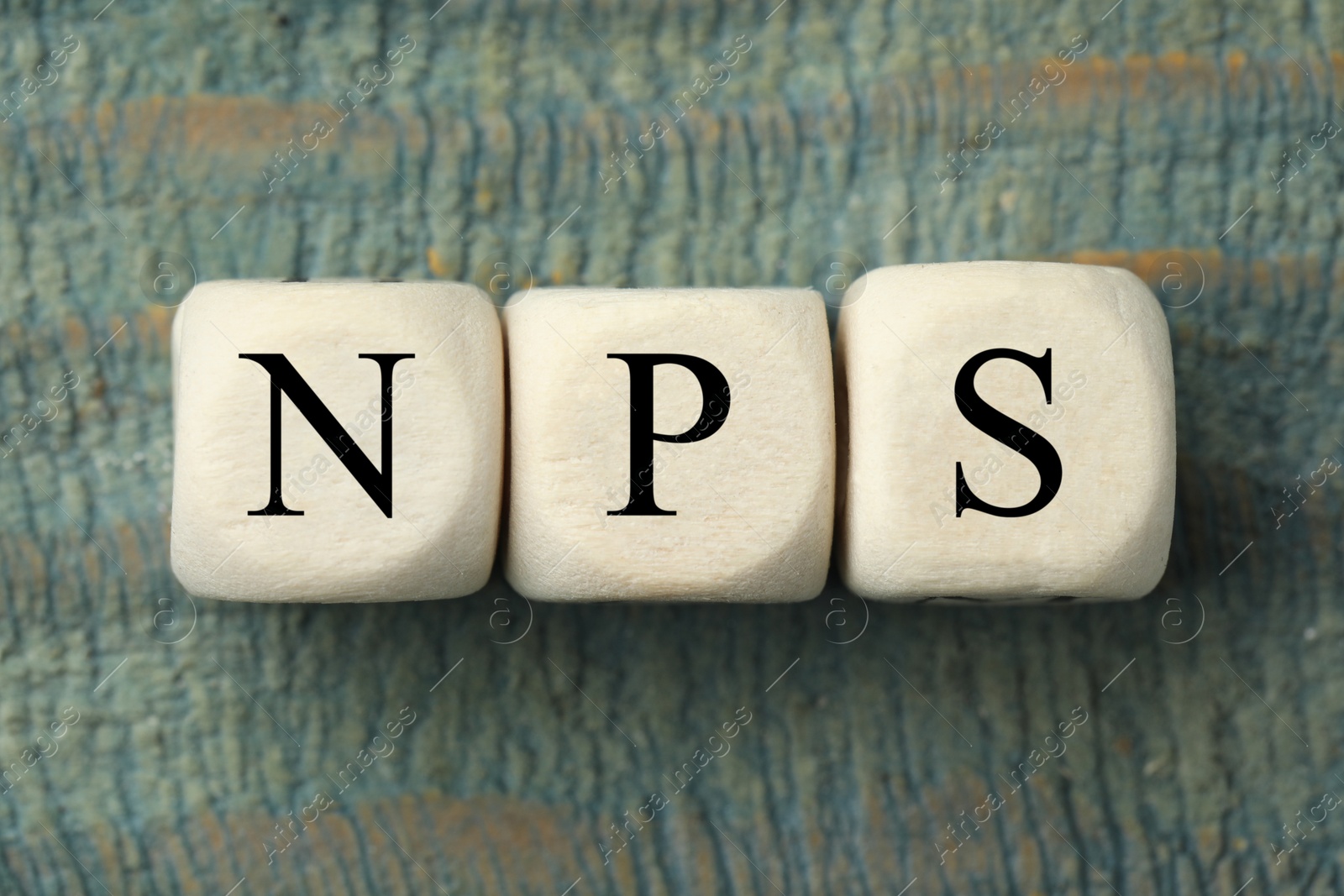 Image of NPS (net promoter score) abbreviation made of cubes on old wooden table, top view