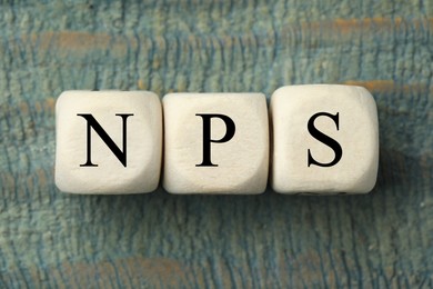 Image of NPS (net promoter score) abbreviation made of cubes on old wooden table, top view