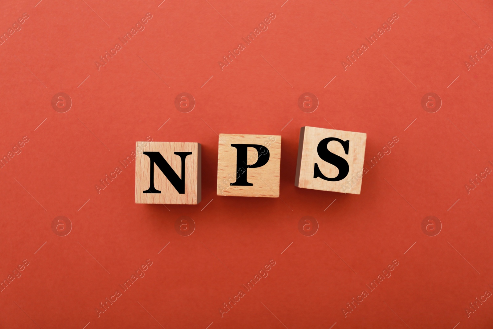 Image of NPS (net promoter score) abbreviation made of wooden cubes on red background, top view