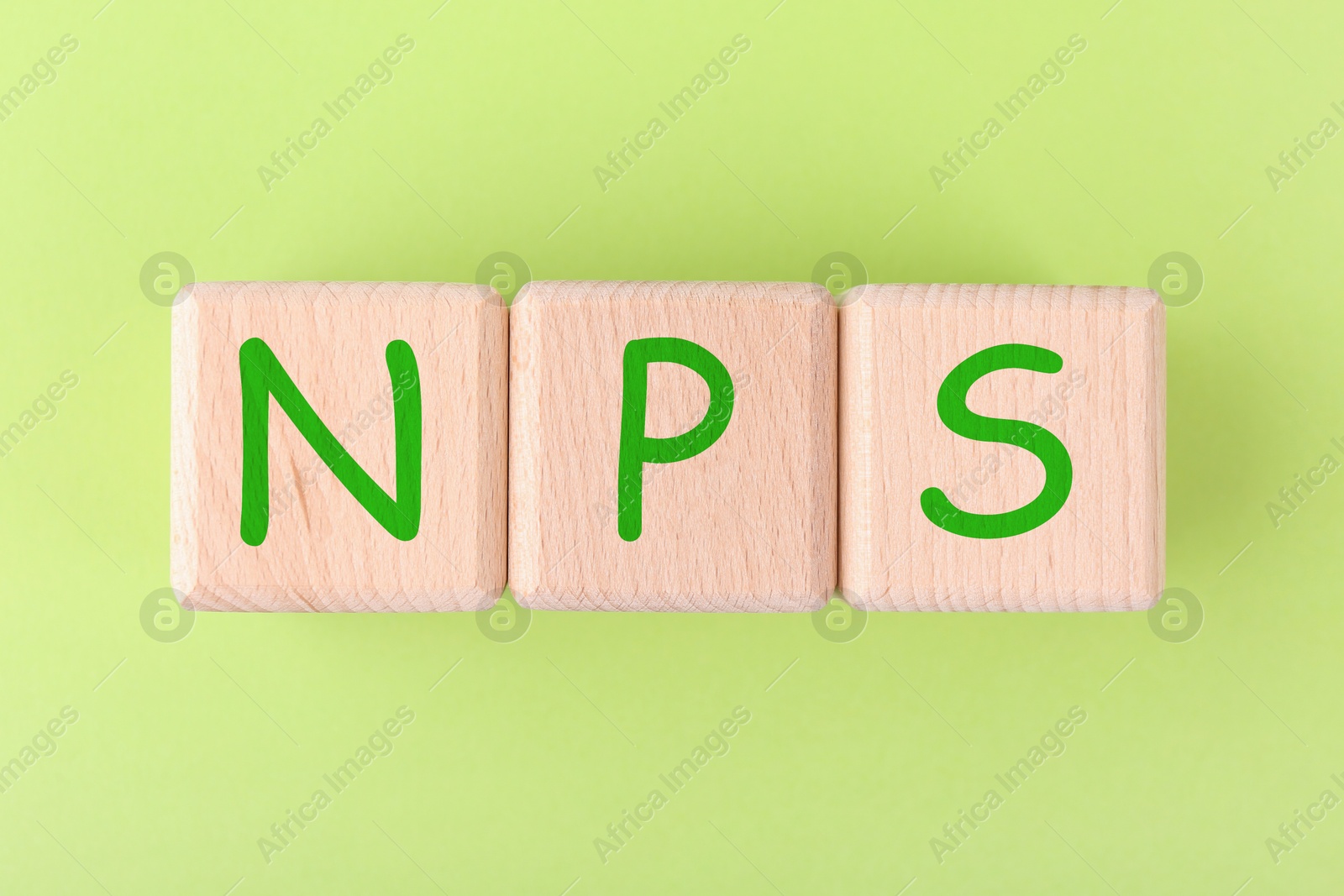 Image of NPS (net promoter score) abbreviation made of wooden cubes on light green background, top view