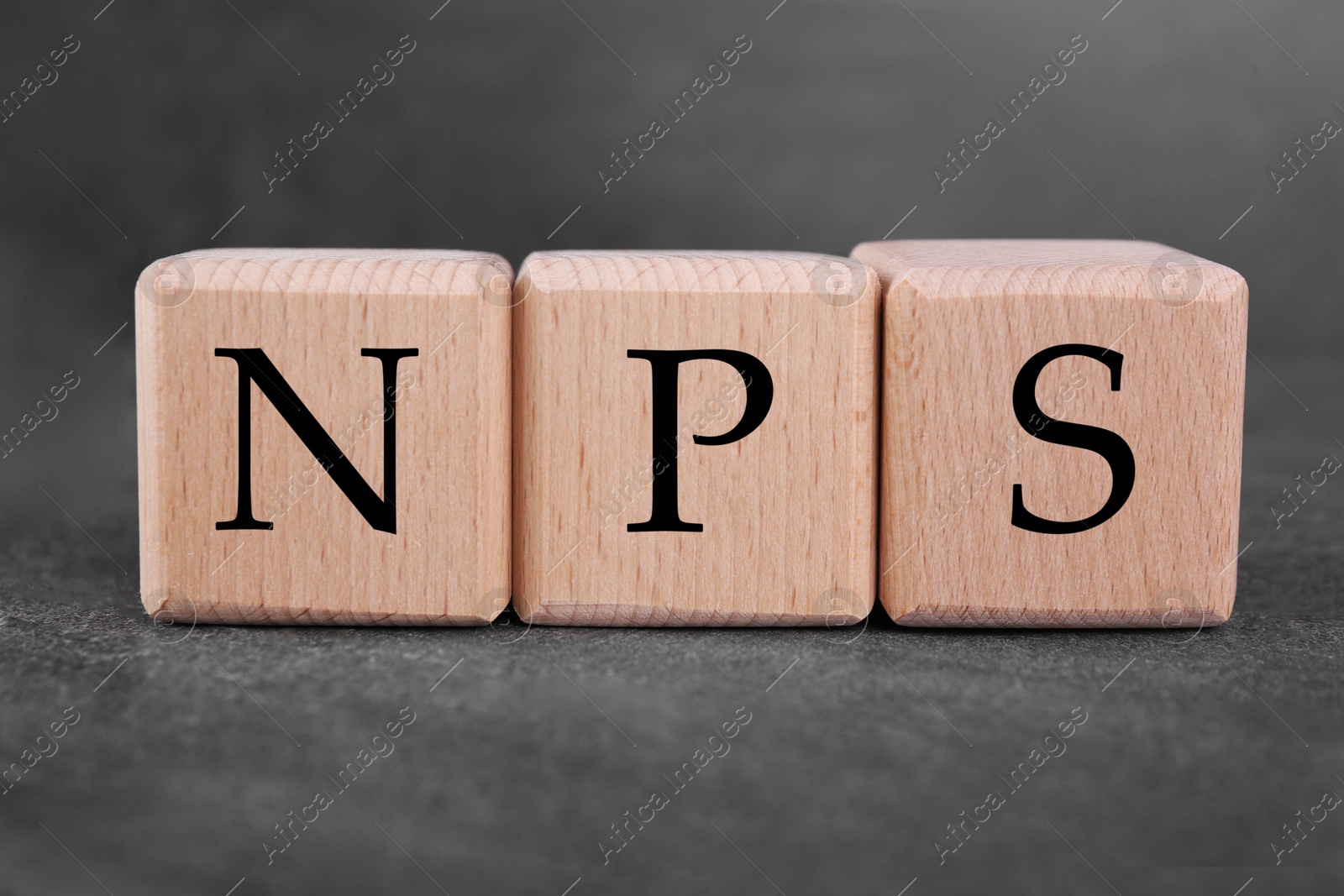 Image of NPS (net promoter score) abbreviation made of cubes on grey table