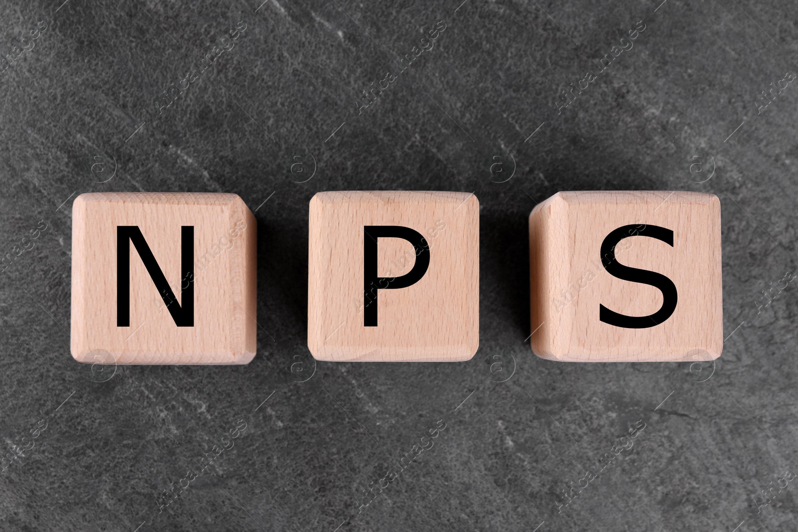 Image of NPS (net promoter score) abbreviation made of wooden cubes on grey background, top view