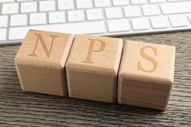 Image of NPS (net promoter score) abbreviation made of cubes on wooden table