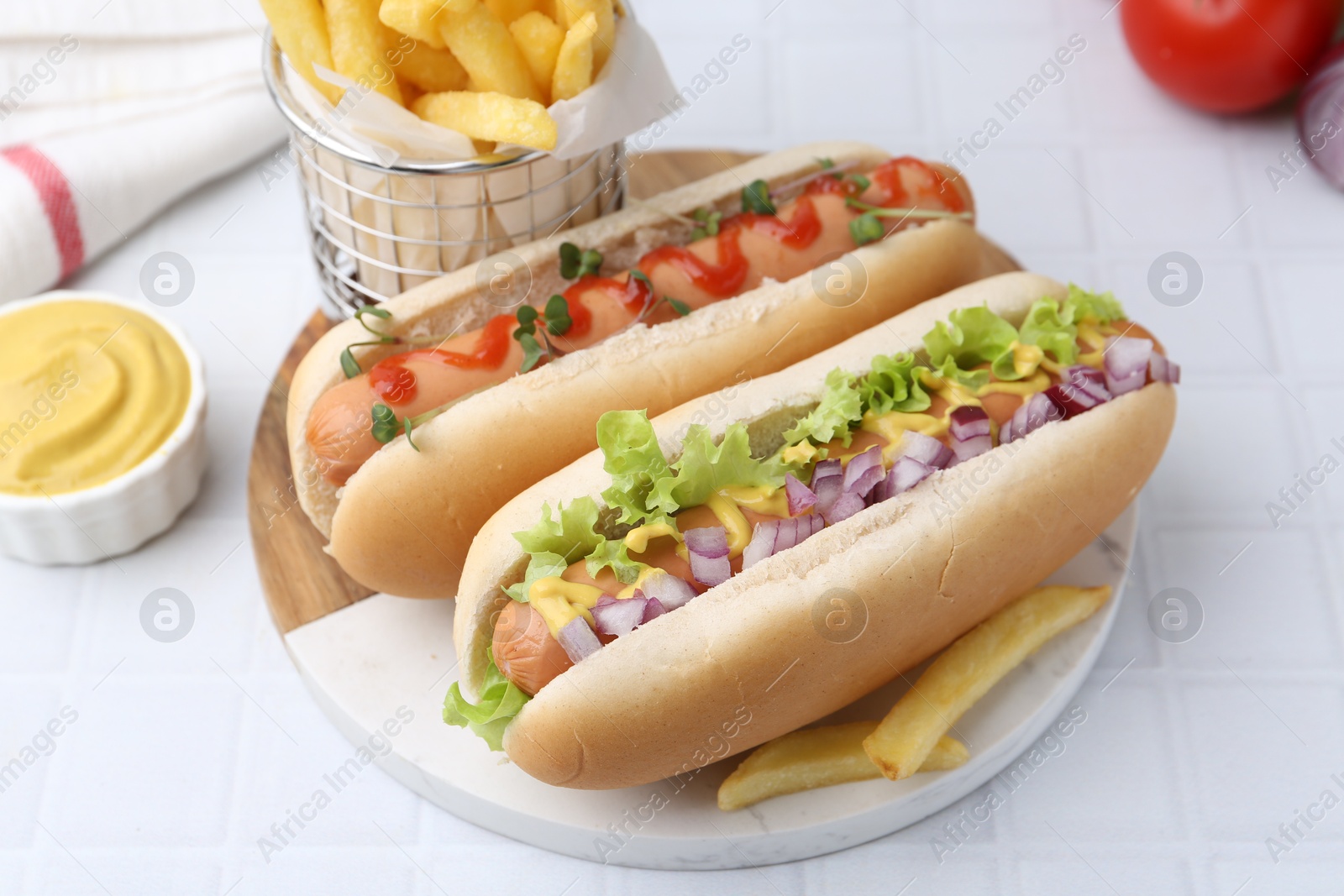 Photo of Tasty hot dogs served on white tiled table, closeup