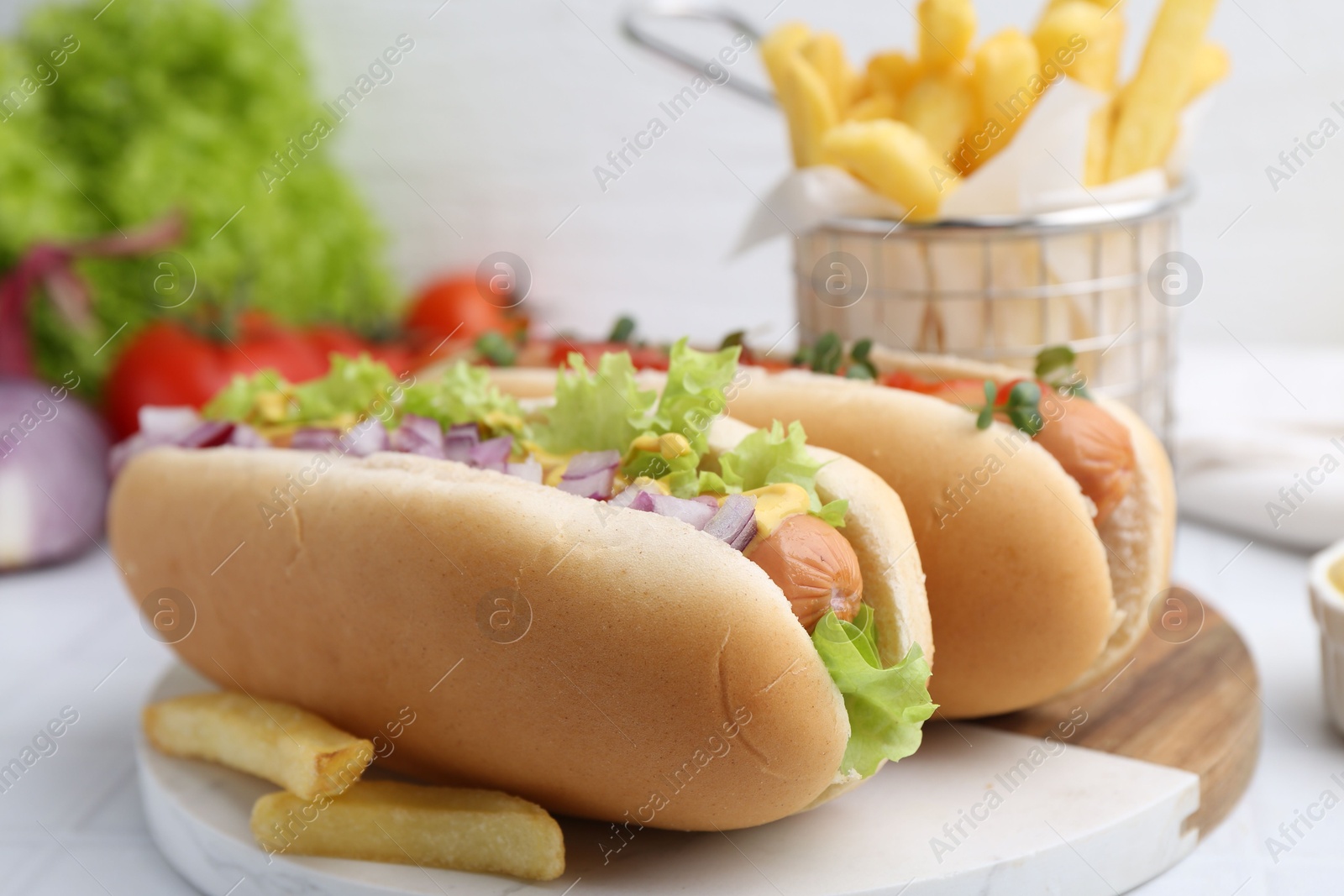 Photo of Tasty hot dogs served on white tiled table, closeup