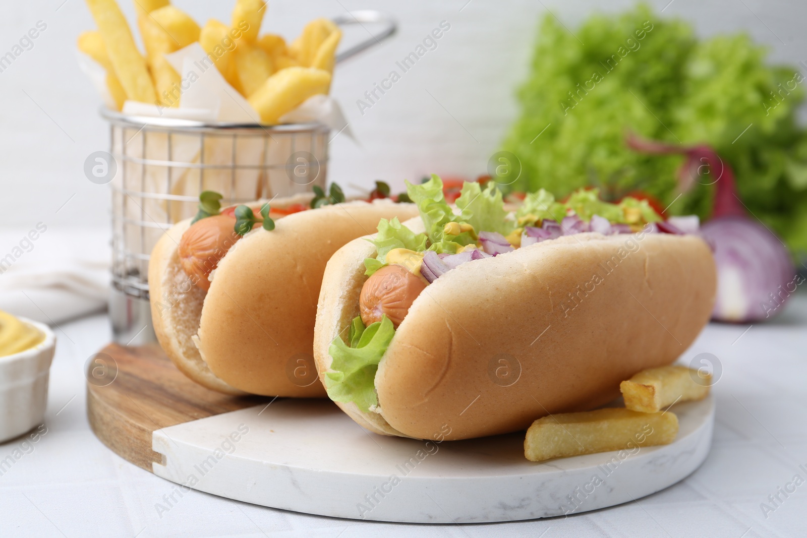 Photo of Tasty hot dogs served on white tiled table, closeup