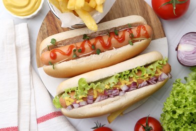 Photo of Tasty hot dogs served on white tiled table, flat lay