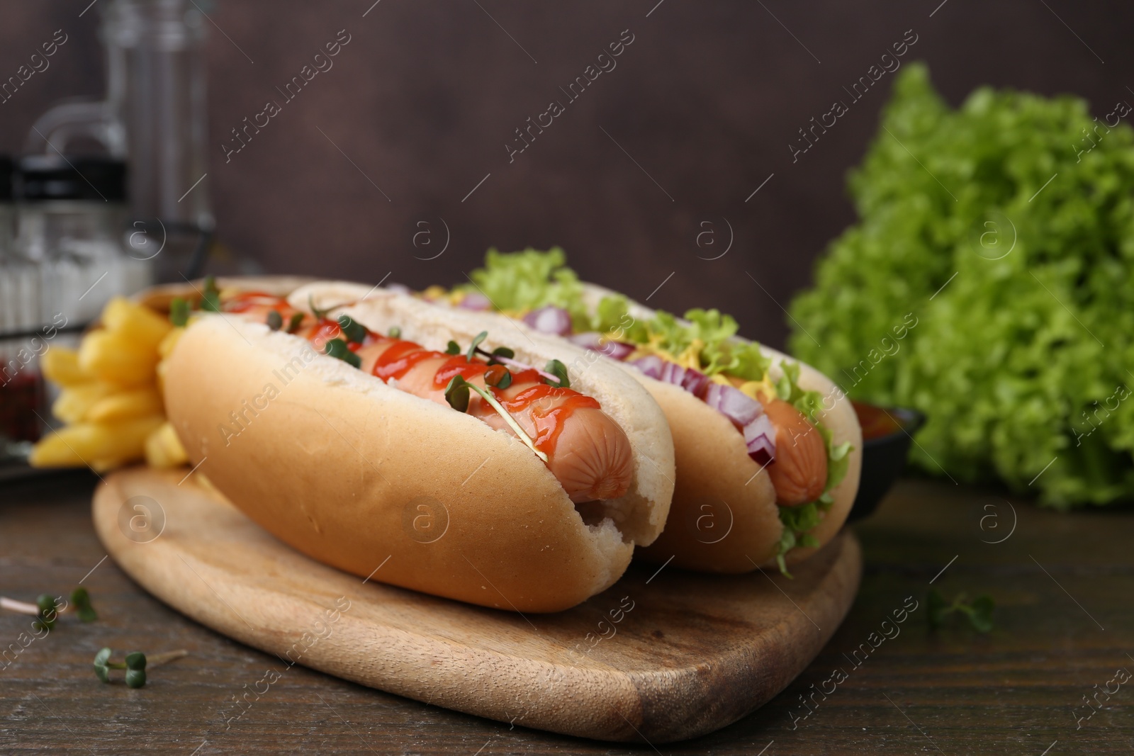 Photo of Tasty hot dogs served on wooden table, closeup