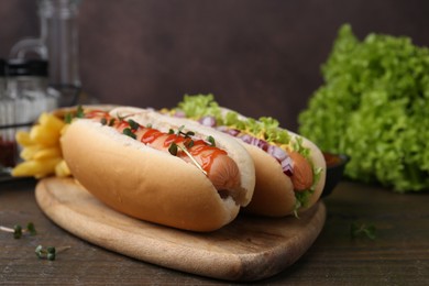 Photo of Tasty hot dogs served on wooden table, closeup