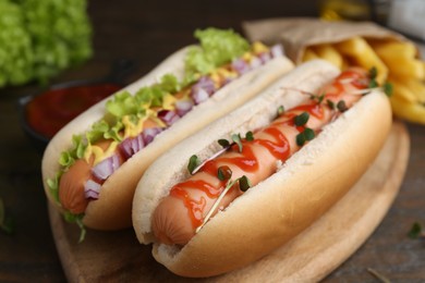 Photo of Tasty hot dogs served on wooden table, closeup