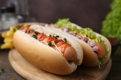 Photo of Tasty hot dogs served on wooden table, closeup