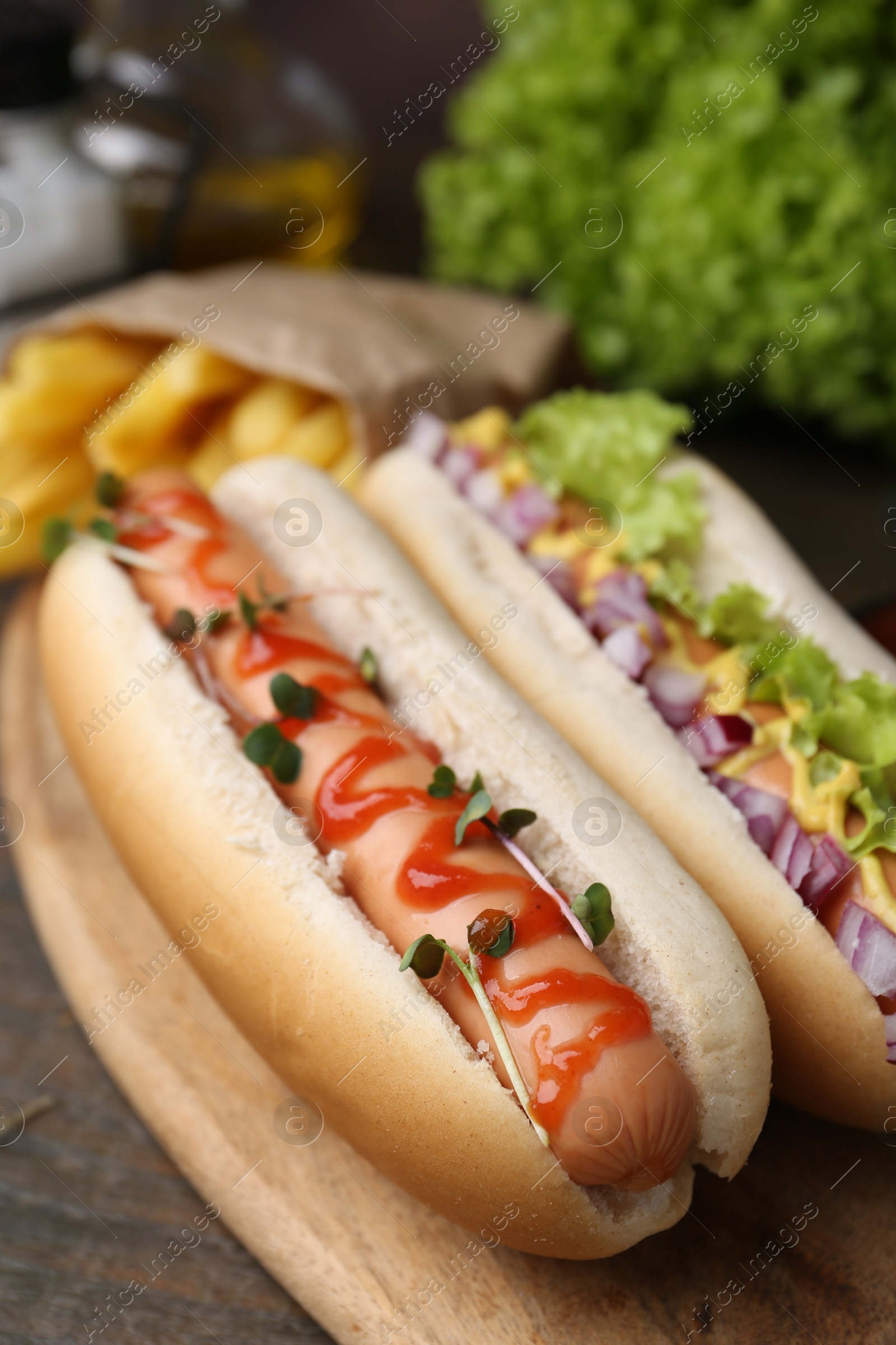 Photo of Tasty hot dogs served on wooden table, closeup