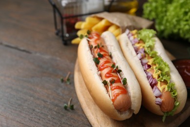 Photo of Tasty hot dogs served on wooden table, closeup. Space for text