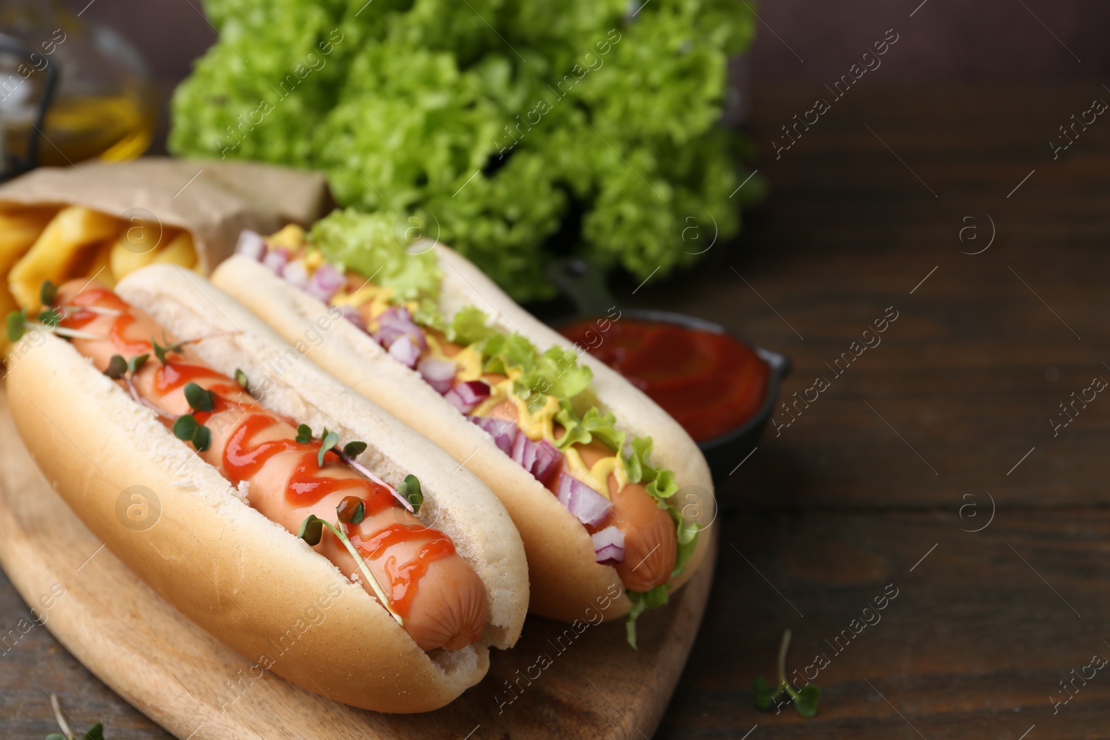 Photo of Tasty hot dogs served on wooden table, closeup. Space for text