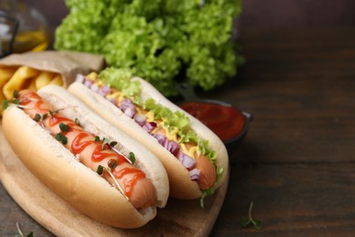 Photo of Tasty hot dogs served on wooden table, closeup. Space for text