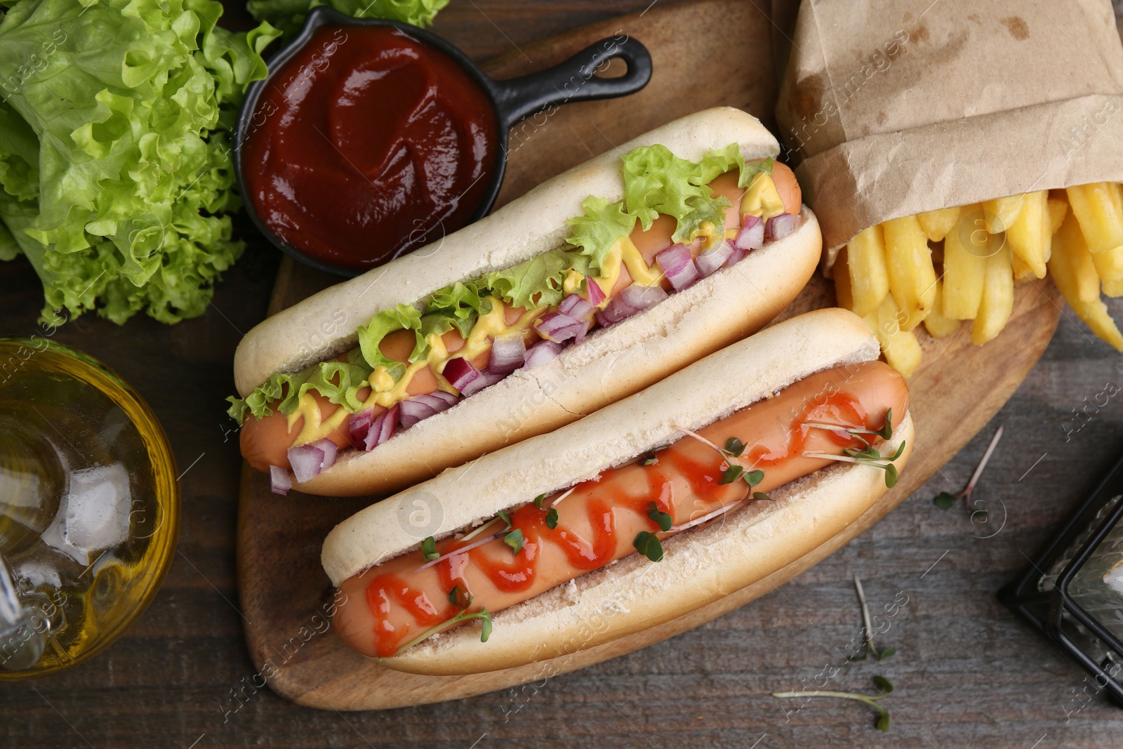 Photo of Tasty hot dogs served on wooden table, flat lay