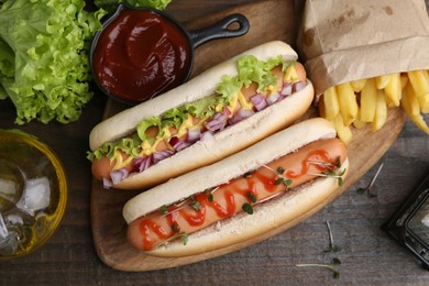 Photo of Tasty hot dogs served on wooden table, flat lay